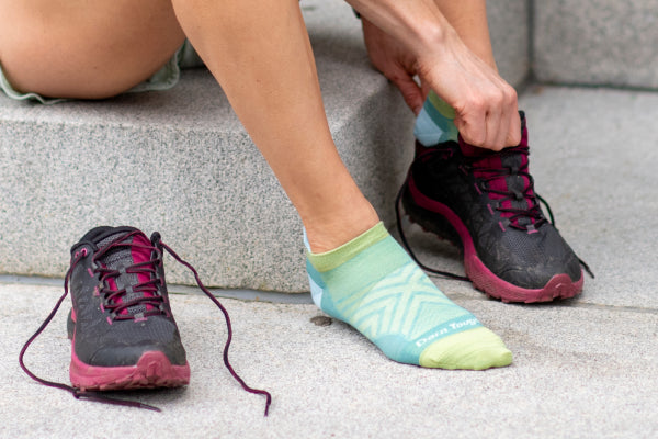 Feet wearing thin run socks (no cushion) about to put on running sneakers