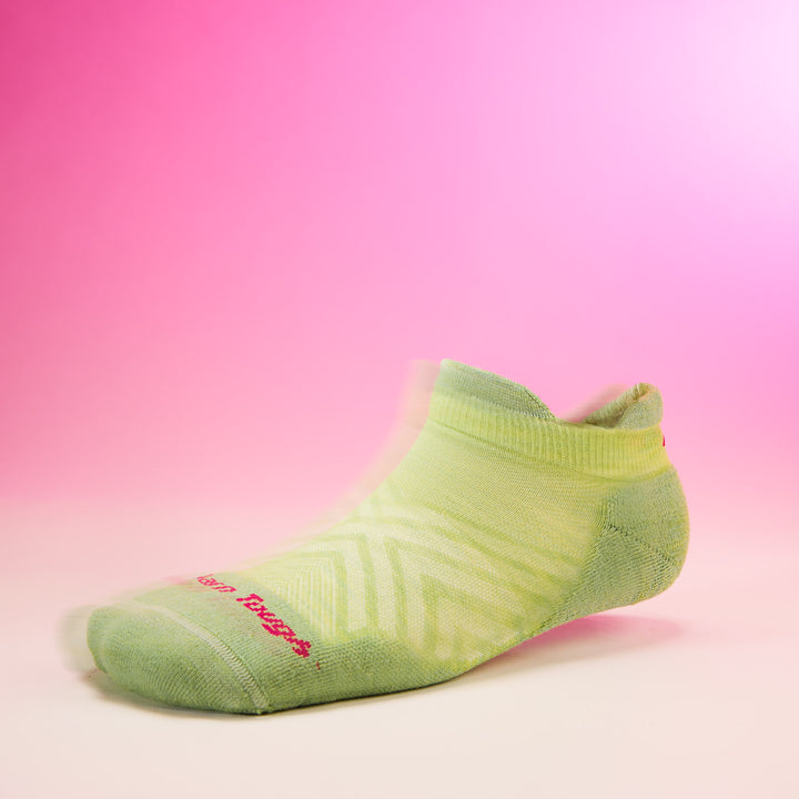 side profile studio shot of womens 1047 no show tab ultra lightweight with cushion in jade with pink background