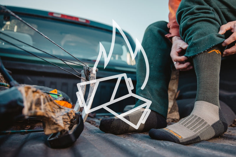 Hunter in truck bed pulling on darn tough merino wool hunting socks for added warmth