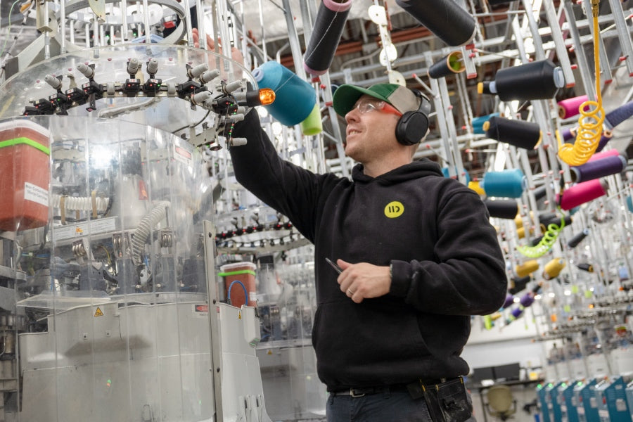 A Darn Tough employee changing out a yarn on a knitting machine