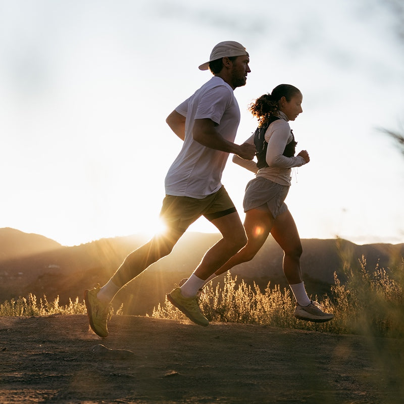 A pair of runners out on trail at sunset wearing matching white Darn Tough running socks