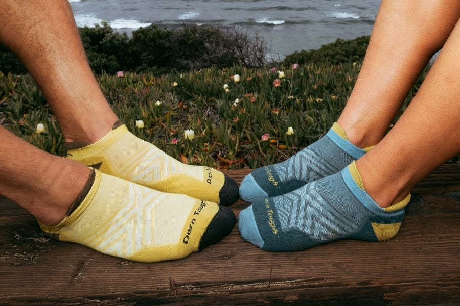 Two sets of feet, one in men's run socks in yellow and the other in women's run socks in blue