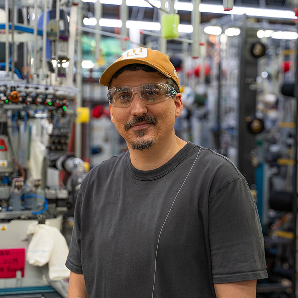 Kris standing in the Mill by a knitting machine