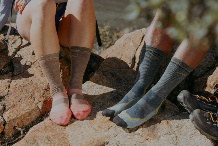 Two pairs of feet wearing coordinated couples socks