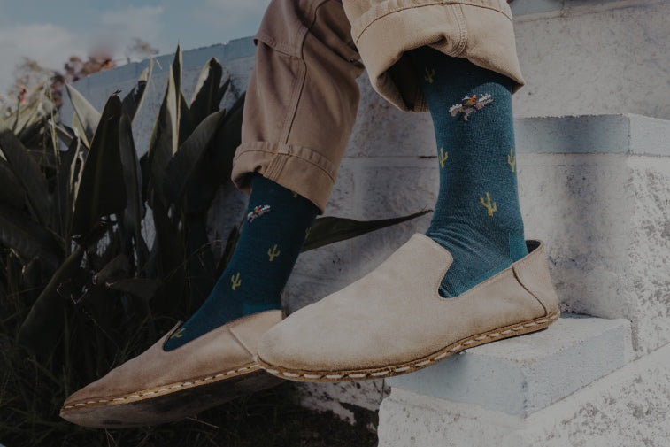 A pair of feet in men's socks with cowboys and cacti