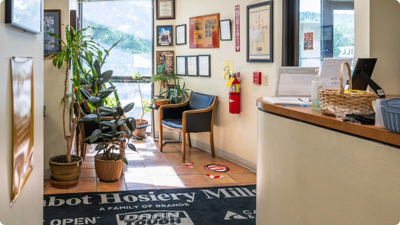 The front lobby at the Darn Tough Northfield Mill, a room full of plants and seats with a reception desk