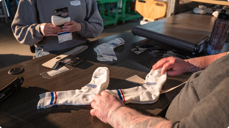 Two people at a table folding Darn Tough socks into pairs and packaging them