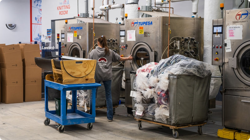 A woman loading up a giant wash and dry unit full of socks
