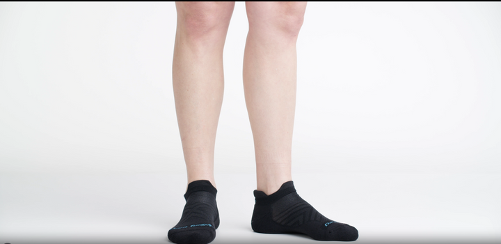 Video of model walking in frame with white background wearing 1047 socks in Black and showing the socks in several angles